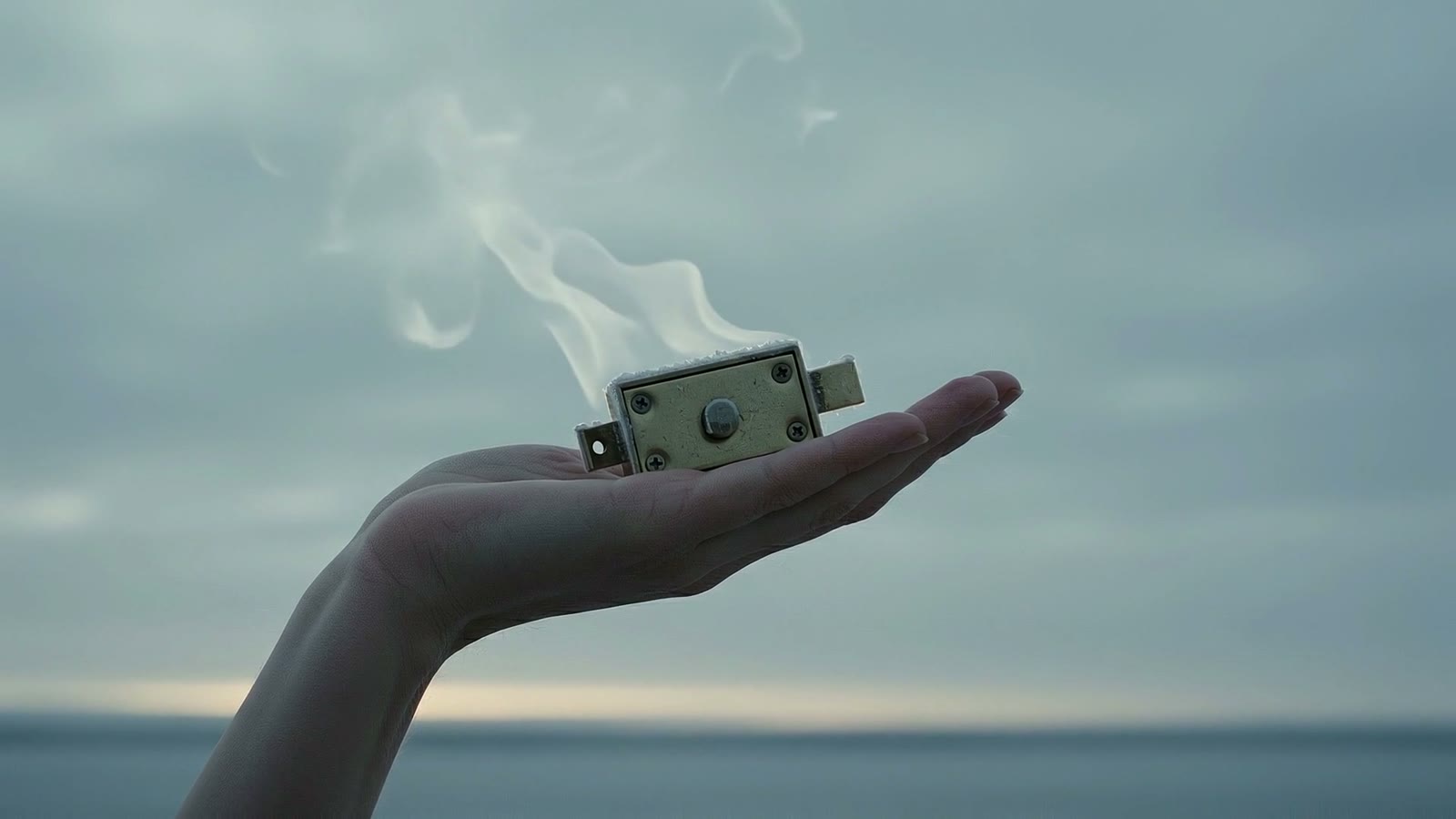 A cold brass latch resting in an open palm, cold vapour rising from the metal.