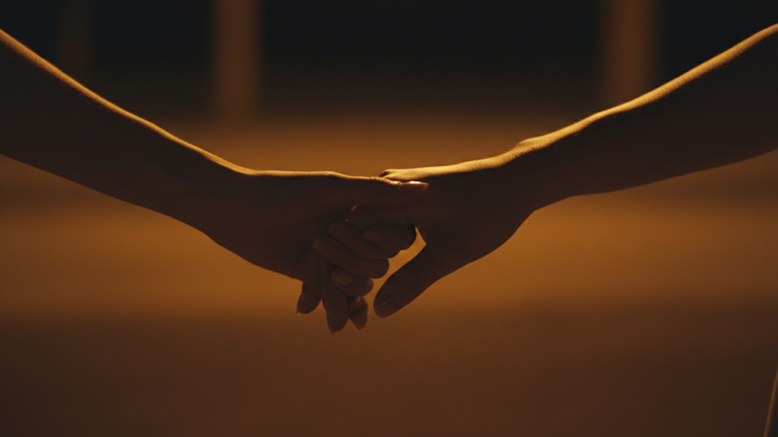 Two hands holding, rimmed in gold light.